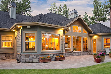 service-windows-doors Beautiful modern home in Calgary with architectural shingle roofing and large illuminated windows at sunset